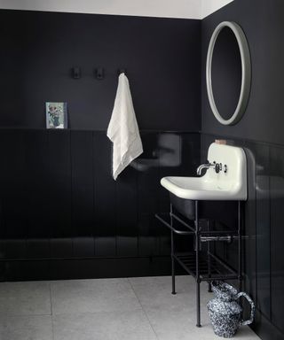 black bathroom ideas, monochromatic bathroom with tongue and groove in gloss finish, walls in matte black, white mirror, towel and basin, pale grey floor