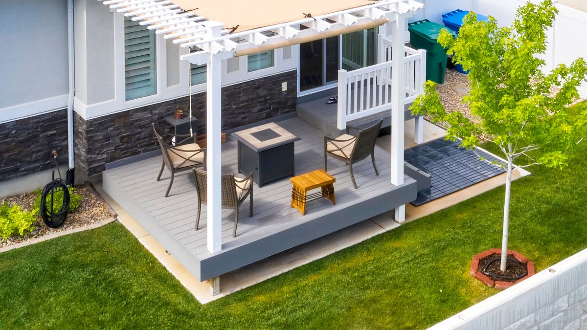 Small grey decking area in garden on top of patio