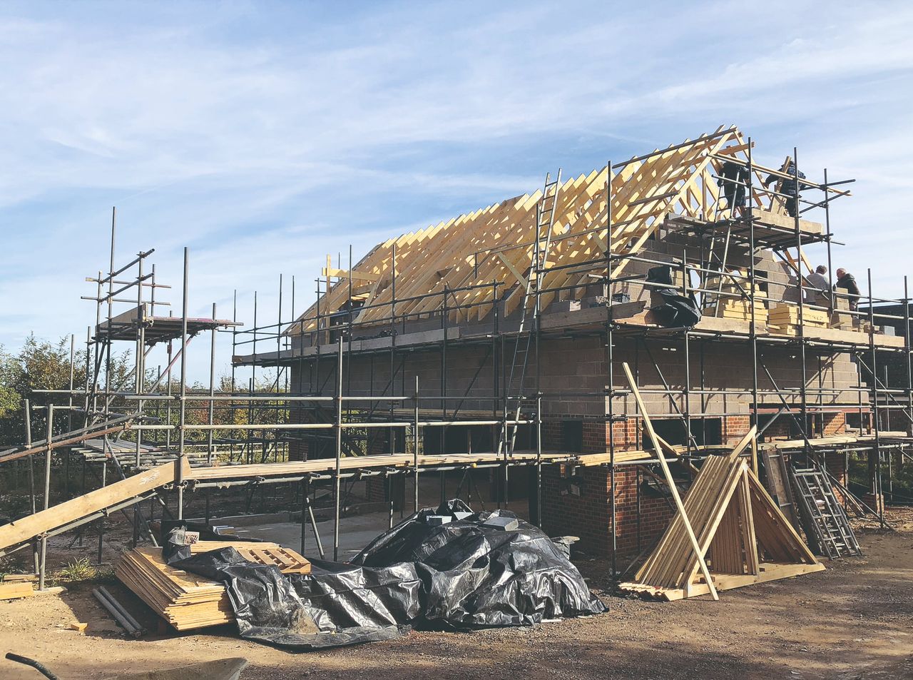 A house surrounded by scaffolding having its timber roof installed