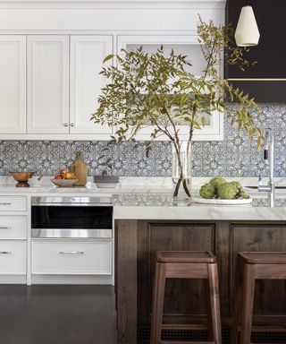 White kitchen with wood island and bar stools and patterned backsplash