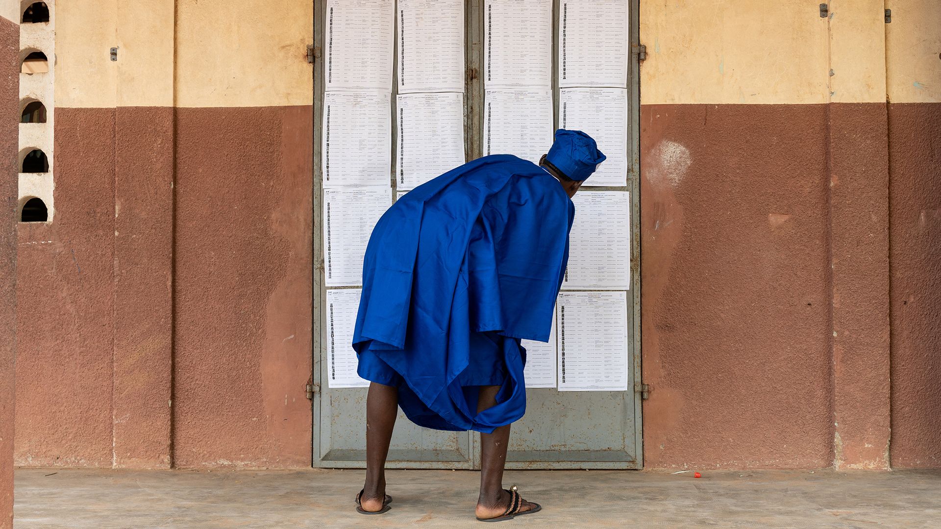 
                                A man inspects the voter rolls at a polling station during the presidential election in Lokossa, Benin
                            