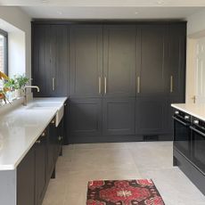 Floor-to-ceiling dark grey kitchen cabinets with grey concrete-effect floor tiles