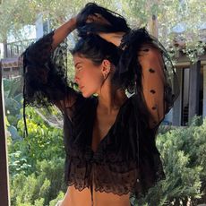 Kylie wears a black lace blouse.