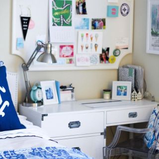 a bed stationed near a desk that serves also as a nighstand