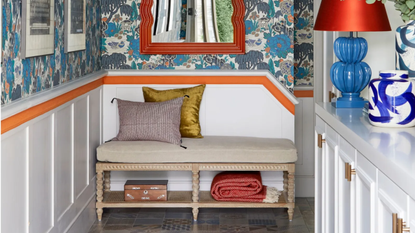 entryway with bold blue wallpaper and orange mirror and wall stripe
