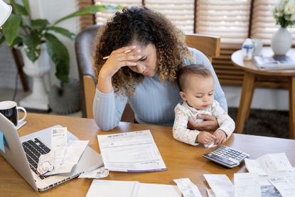 Woman with baby calculating expenses at a desk