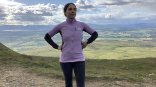 Hiker looking at the camera with hands on hips wearing purple fleece