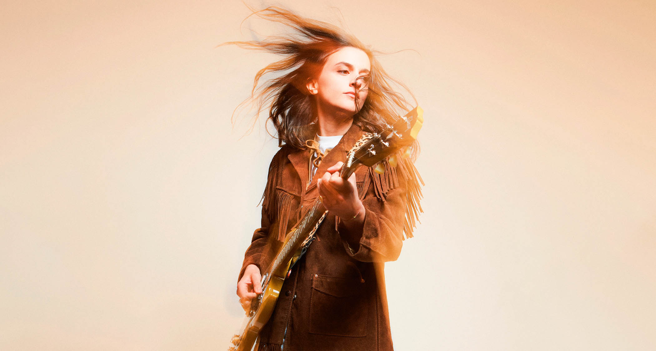 Laura Cox strikes an action pose with a Gibson electric guitar