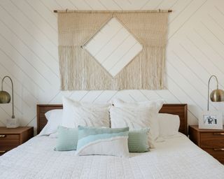 Jenn Im bedroom with macrame hanging, white bedsheets and blue accents