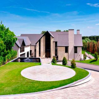 sloping roof house with grass lawn and green trees