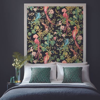 Bright green and pink nature-inspired wallpaper mimics headboard in dark bedroom space