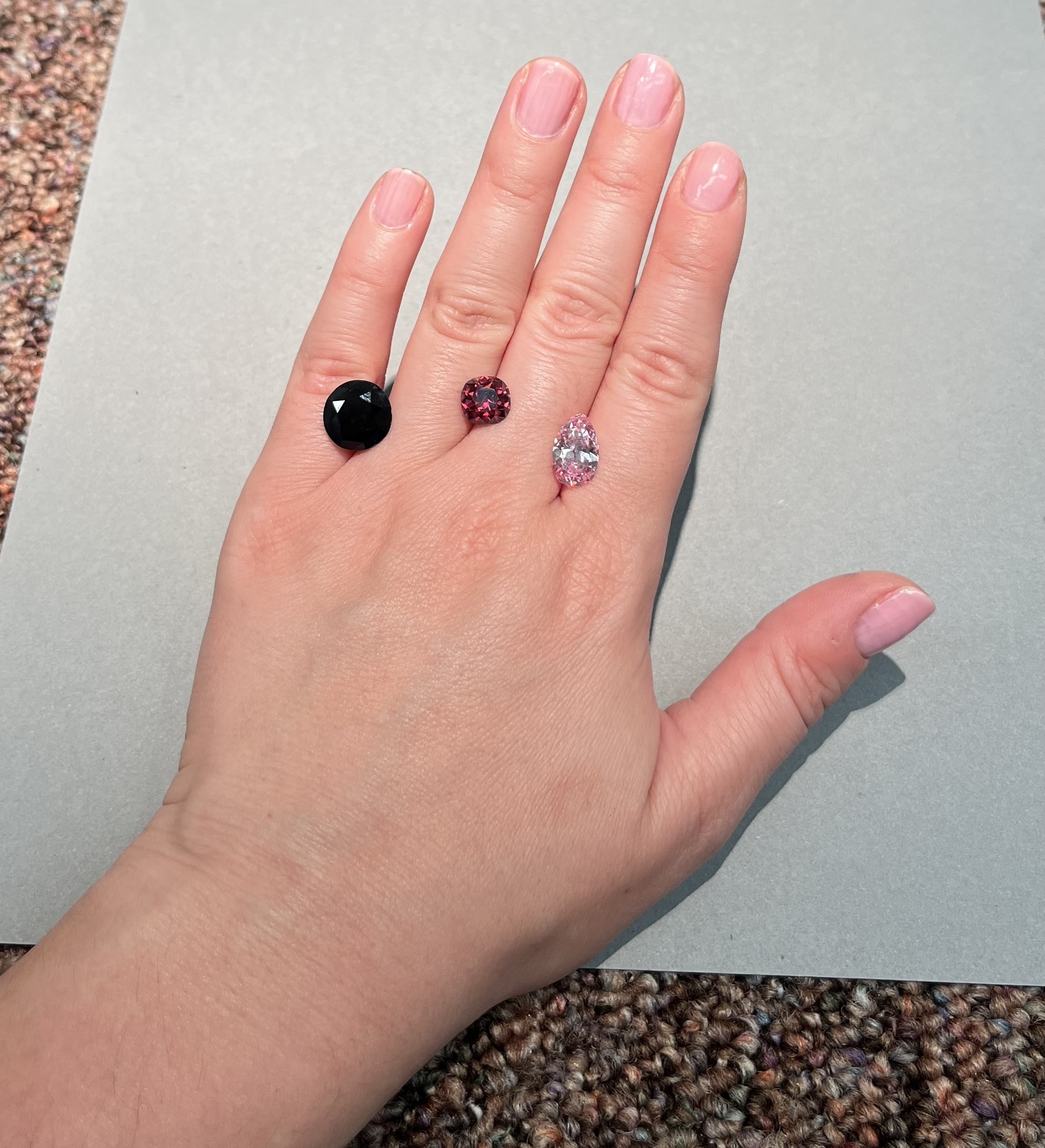 a photo of a person's hands with three diamonds with varying degrees of red hues