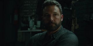 Triple Frontier Ben Affleck looking stoic in a storage container of weapons