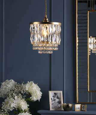 A crystal pendant light hanging in a navy blue living area