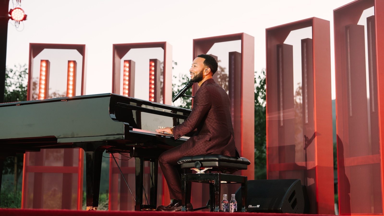 John Legend performing on the piano on a stage at the Robert Mondavi Winery reopening event