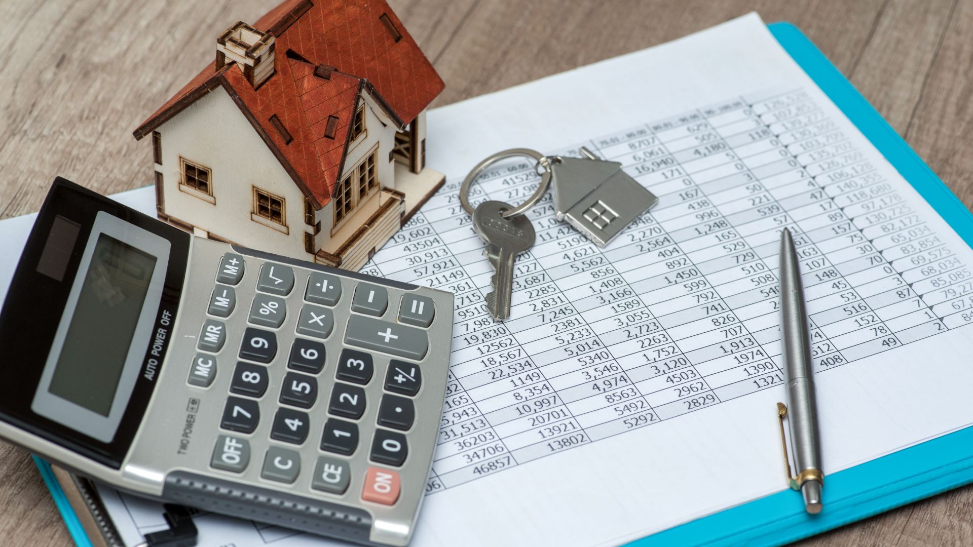 Calculator, mini house, keys and a clipboard