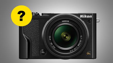 Front view of a black Nikon DL series camera with a Nikkor 6.7-18.5mm f/1.8-2.8 lens and a yellow question mark graphic
