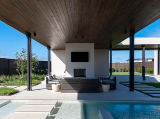 Outdoor living room under roof with sofa, armchairs and TV