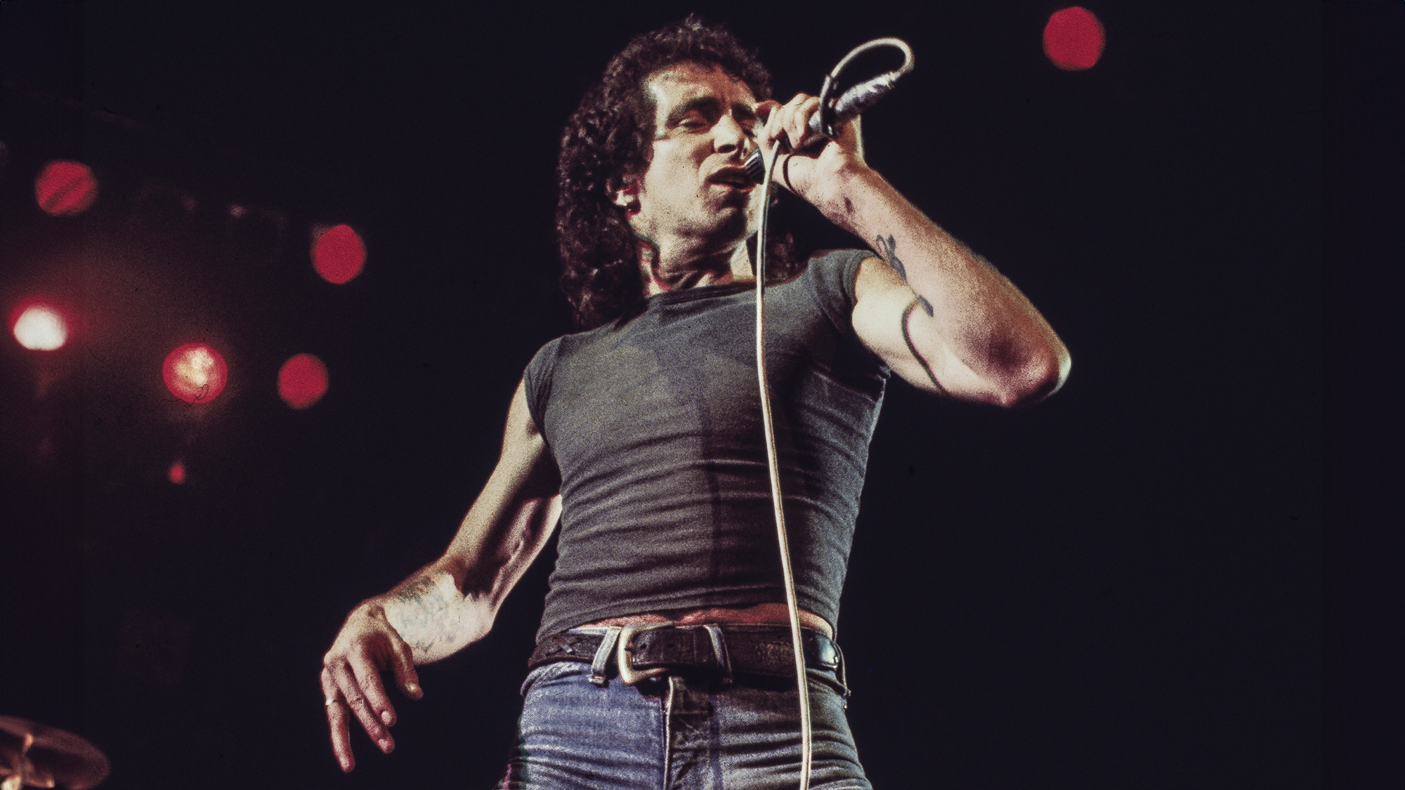 Bon Scott performs on stage with AC/DC, UK, 1976.