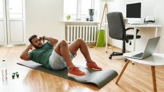 Man performs sit-up abs exercise at home
