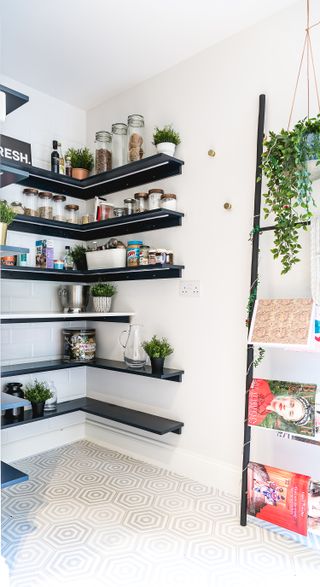 White pantry with black shelves and black wooden ladder