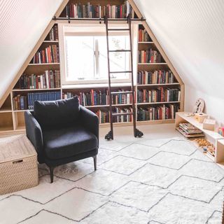 Triangular shaped bookshelf with books with a qhite rug in front of it and a black leather chair on top of it next to woven basket