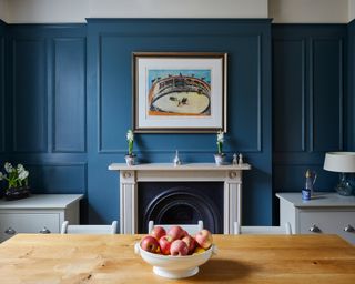 Blue living room with wall panelling above fireplace to frame artwork