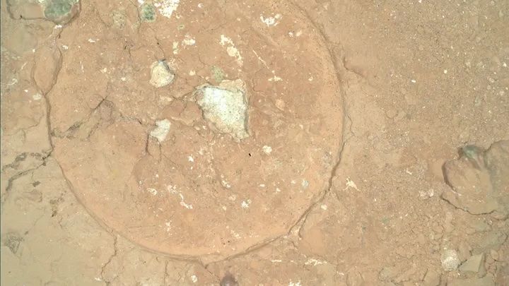 An aerial view of Mars showing green spots in the red rocks