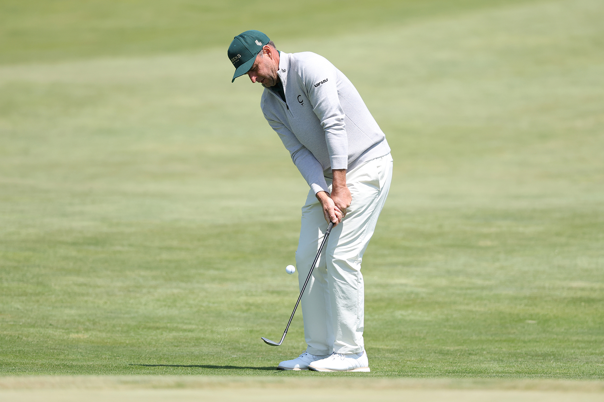 Richard Bland hitting a chip shot from off the green with the ball just leaving the club face
