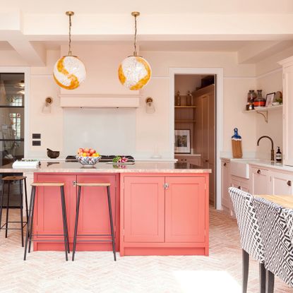 Shaker kitchen with large coral kitchen island and two large globe pendant lights above