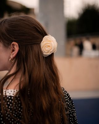 editor Halie LeSavage stands on a track at the Baum Und Pferdgarten show wearing a half up half down hairstyle with a rosette clip