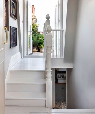 white painted landing area, painted wooden stairs, open doors leading to a roof terrace