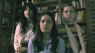 Madeleine McGraw and Violet McGraw stand behind Sarah Lind flanking her in the living room in The Curse of the Necklace.