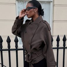 Marilyn wears a brown coat with black sunglasses.