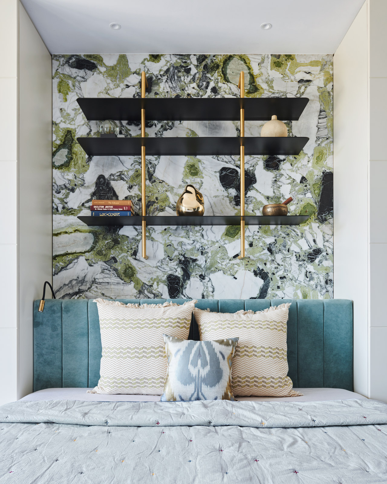 A bedroom with a stone wall behind the bed