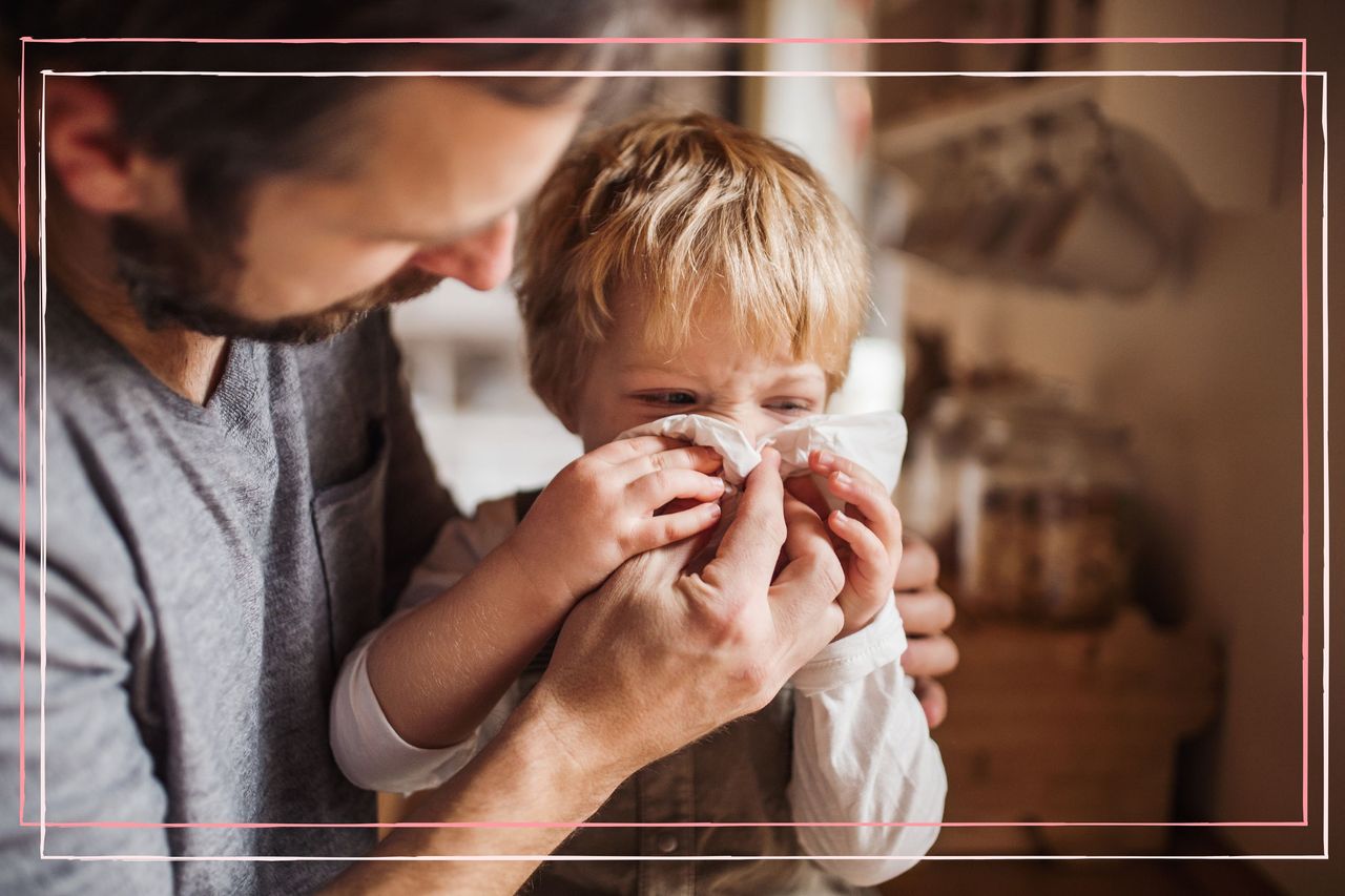 Father wiping toddler son&#039;s nose as he suffers from common symptoms of coughs and colds in babies and children