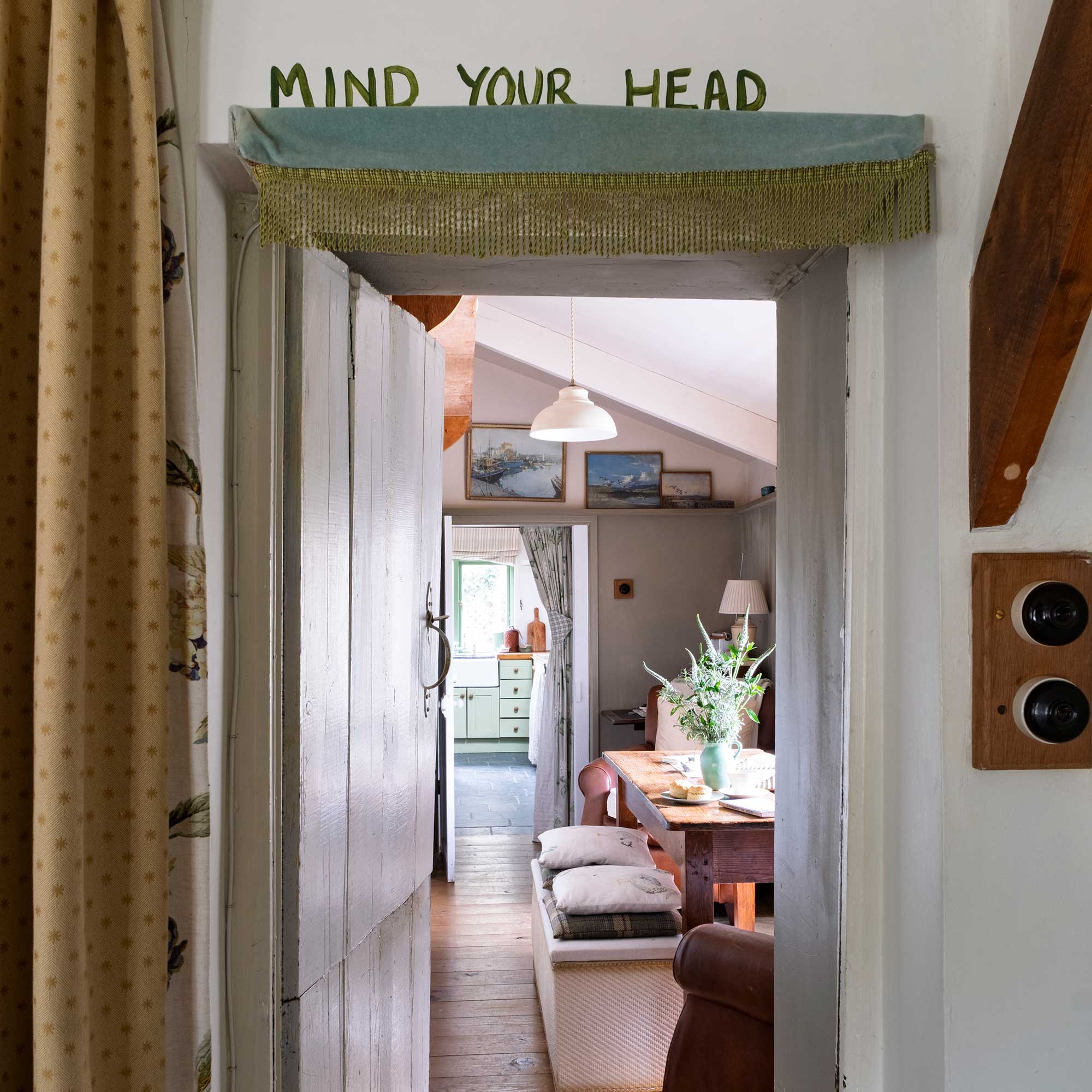 view through low doorway in a cottage to narrow dining room and kitchen