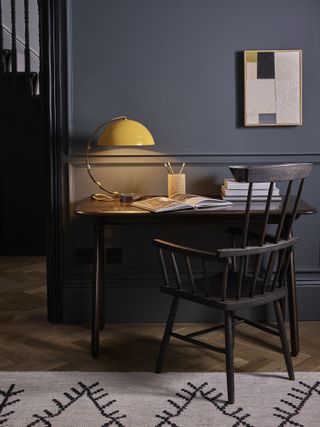 Matching dark wall paint and furniture and contrasting yellow lamp and hint of yellow in wall hanging