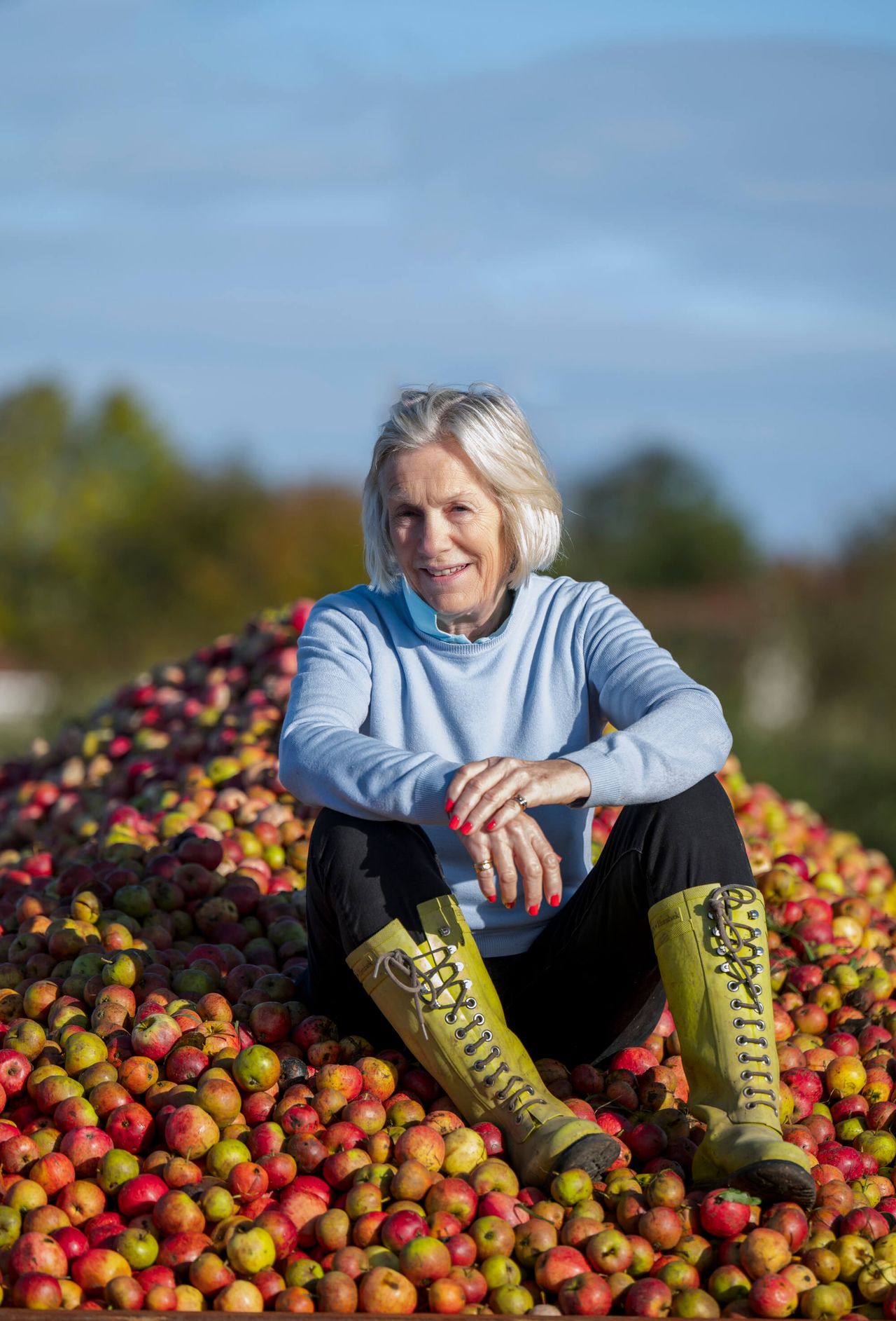 Woman sat on pile of apples.