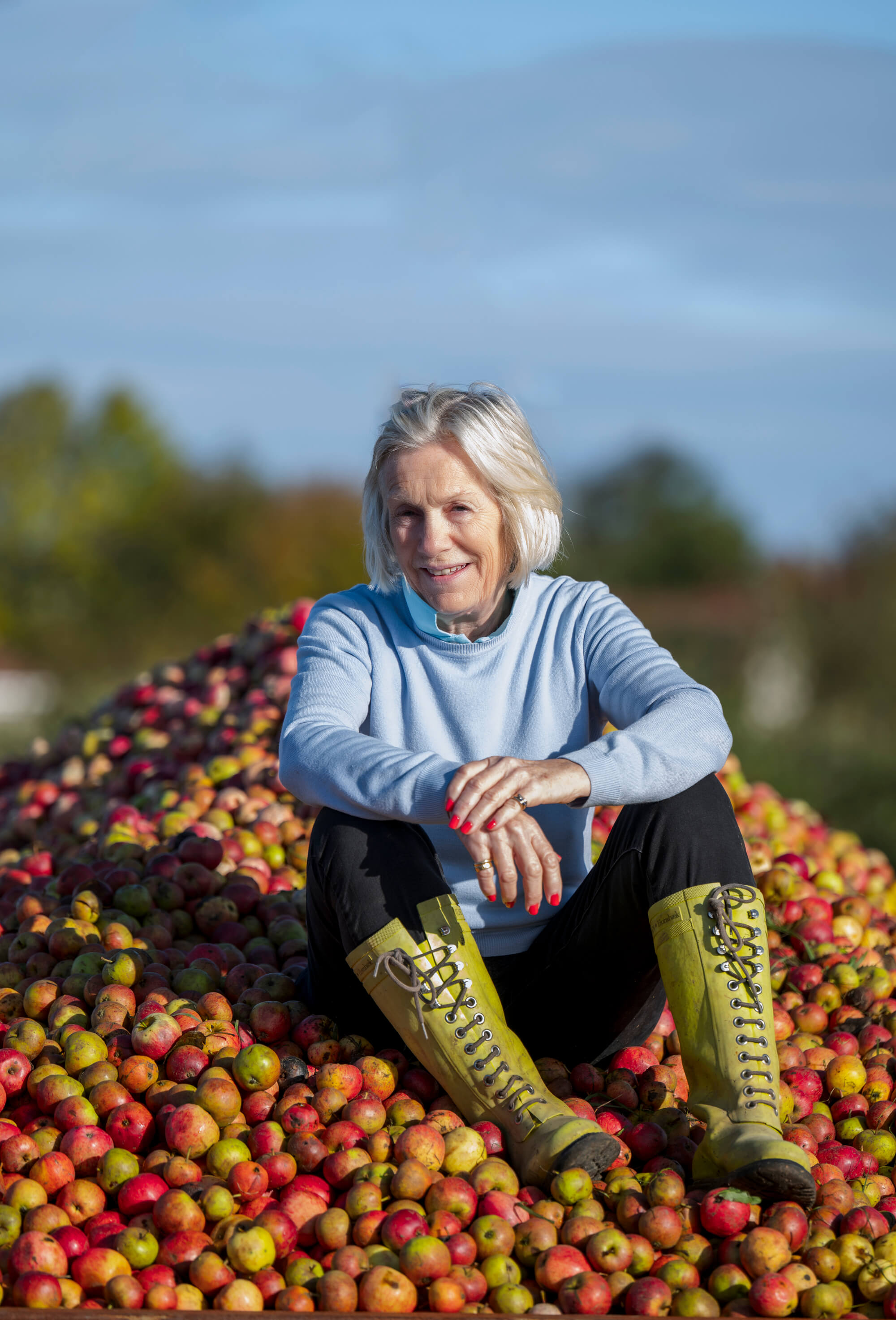 Woman sat on pile of apples. 