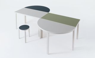 'S' shaped table with broad lines of white, green and blue with round stool next to it.