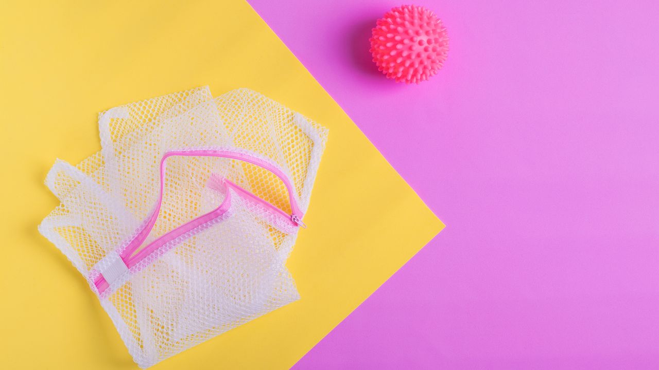 Laundry bag and ball for washing machine on geometric pink and yellow background