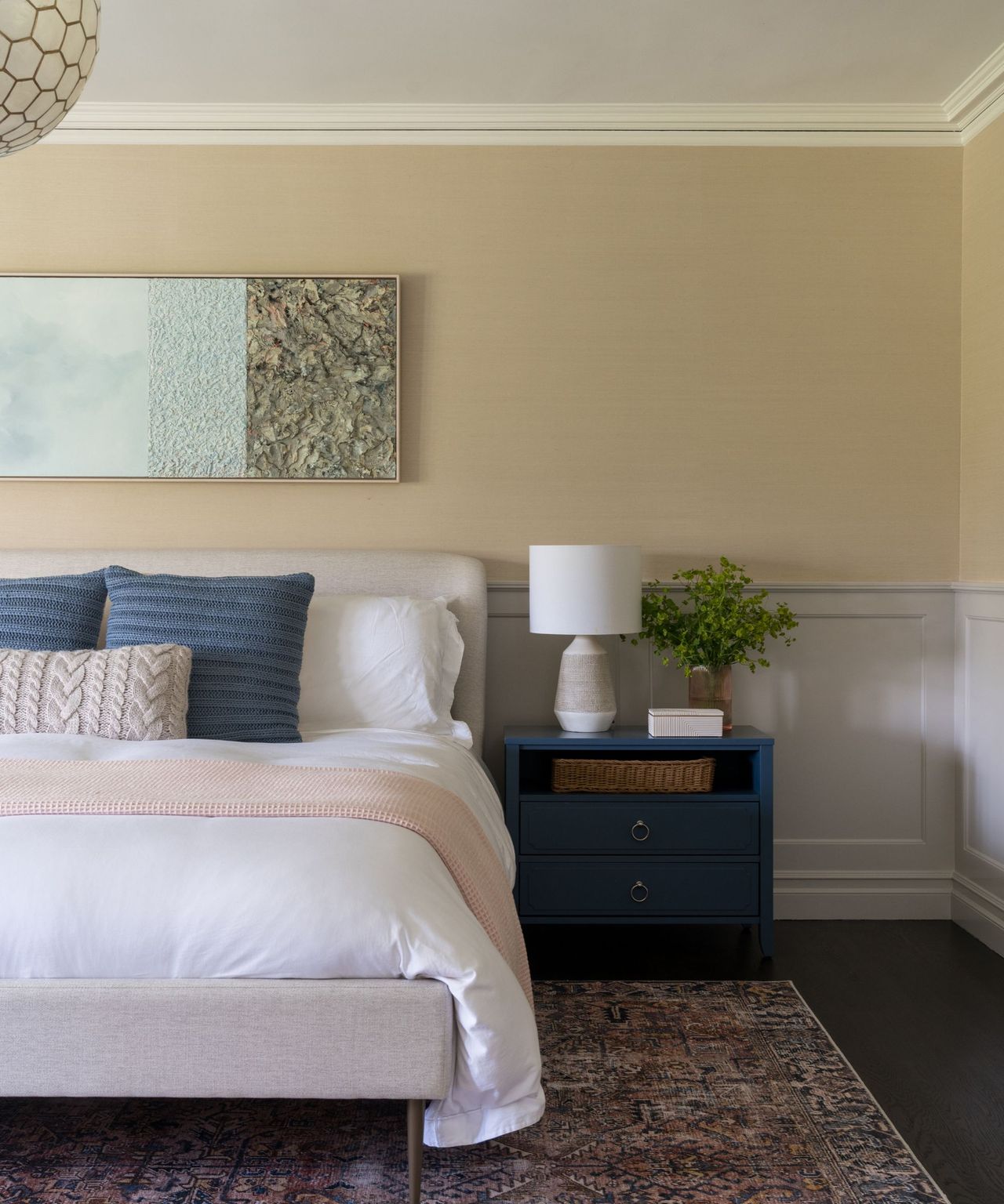 A bedroom with yellow neutral walls and a wooden side table