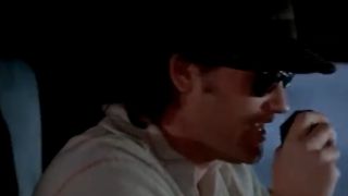 Kurt Russell wearing a hat and sunglasses and talking into a CB radio in Big Trouble In Little China