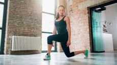 Woman performing curtsy lunge in sparse indoor space