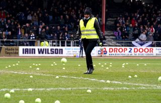 A steward clears tennis balls off the Dundee pitch at the weekend