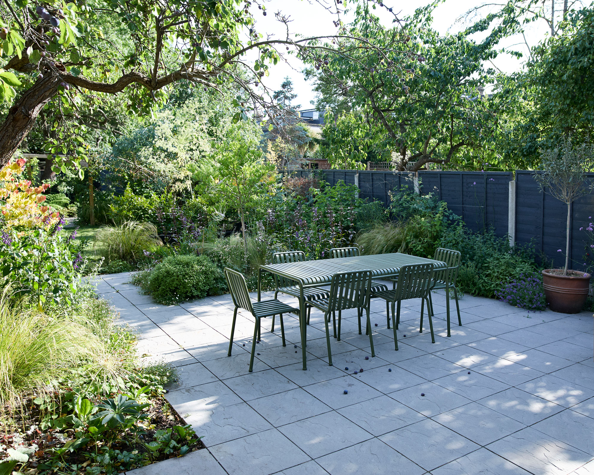 modern garden design with patio, black fence, planting and outdoor furniture set