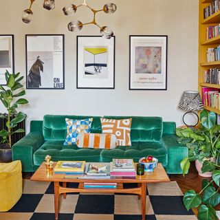 Green sofa in a living room with a retro coffee table and prints on wall