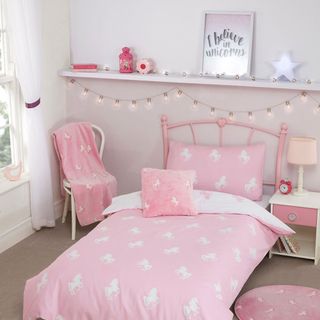 pink colour bedding having unicorn design and bed side tabel and chair