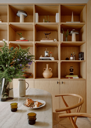 A dining room with a wall shelf storage unit